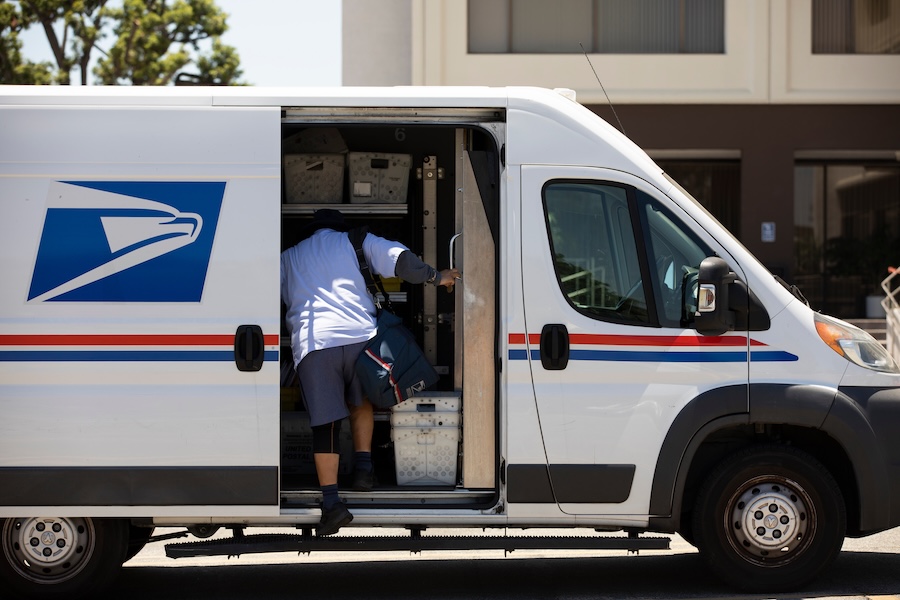 USPS driver getting into side door of delivery van