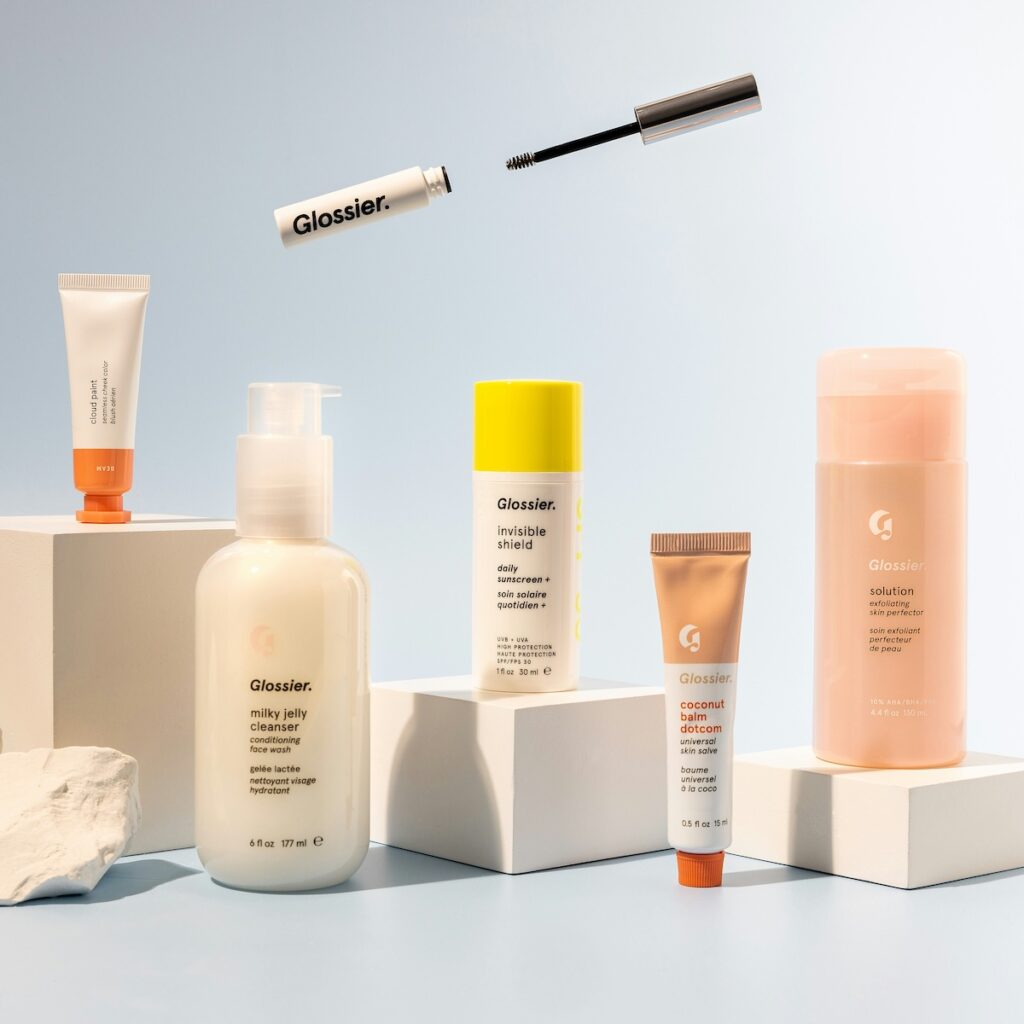 Glossier brand beauty products displayed on a table